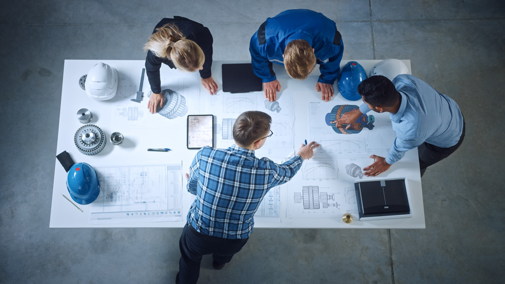 Team of Industrial Engineers Lean on Office Table, Analyze Machi